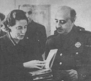 Franco condecora a una enfermera de la Sección Femenina. Le acompaña Fernández Cuesta. La aportación femenina a la guerra fue heroica y sacrificada.