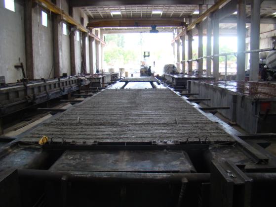 Gato hidráulico utilizado para tesar los torones de los paneles en la planta de producción de Flasur Gato hidráulico Armaduras pasivas colocadas en un molde Vertido del hormigón en un molde Sacando