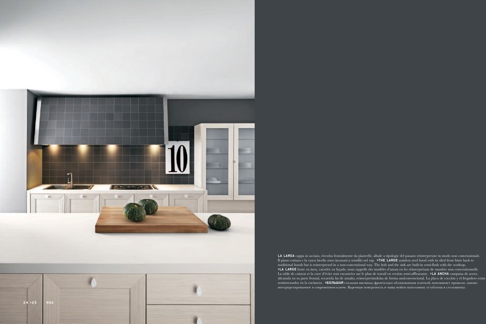 >the large stainless steel hood with its tiled front hints back to traditional hoods but is reinterpreted in a non-conventional way. The hob and the sink are built-in semi-flush with the worktop.