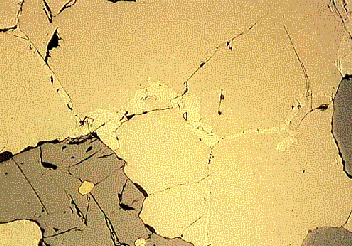 PIRROTITA- imagen 2 250 µm Los cristales de pirrotita (café clara) presentan cristales granulares de pentlandita (café clara, alta reflectancia, centro izquierda) a lo largo de sus bordes, pero están