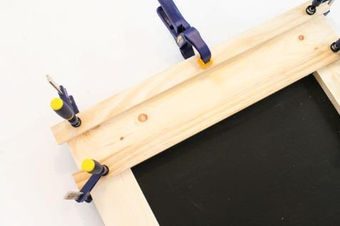 5. Añadir la cabecera decorativa Aplica pegamento para madera en la parte posterior de las molduras de 1 x 5 x 63 cm de la cabecera de la pizarra.