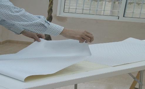 Desdoblar el papel encolado por un extremo y extender sobre la superficie a cubrir, alisando con el cepillo de empapelar, para evitar la oclusión de aire. Corte del papel 5.