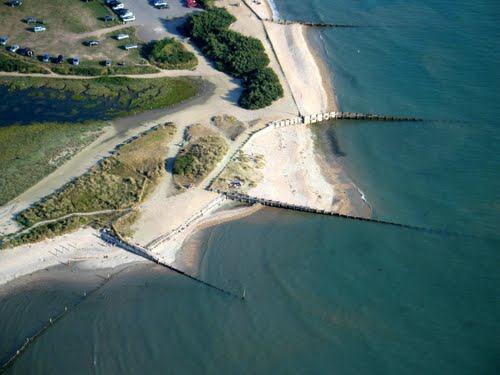 - Erosión a largo plazo: Día a día el oleaje llega a todas las costas y mueve la arena de las playas en un movimiento aproximadamente paralelo a la costa, lo cual se conoce como el transporte litoral.