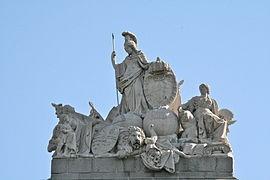 Se encuentra coronada por un grupo escultórico en piedra diseñado por José Ginés y esculpido por Ramón Barba y Valeriano