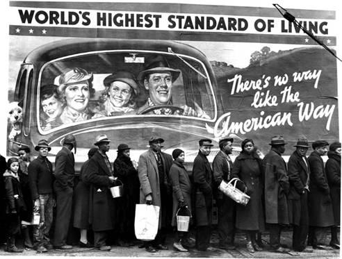 Un grupo de norteamericanos de color hacen cola para obtener algún tipo de ayuda bajo un cartel que proclama que EEUU tiene el mayor nivel de vida del mundo y que no hay ninguna forma de vida como la