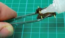 Presiona el alambre de latón por el primer par de agujeros para los ejes y córtalos