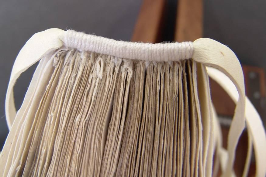 Cosido de los cuadernos a través de los orificios de la costura original con hilo de lino Barbour nº18 sobre tres nervios naturales dobles de piel de curtido al alumbre, mediante costura a punto