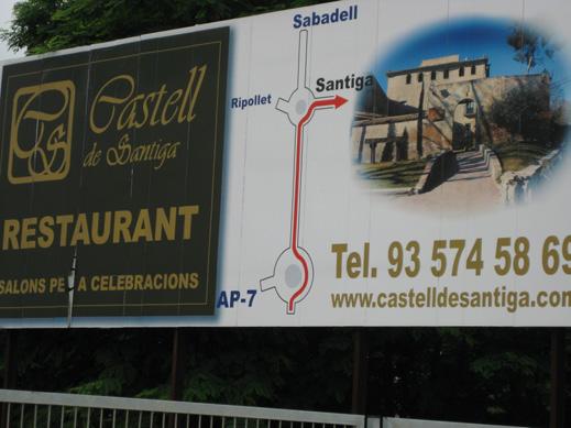 Publicitat a la carretera, anunciant el restaurant del castell de Santiga. A l esquerra antic camí rural a l interior dels polígons industrials actuals, i la senyalització.