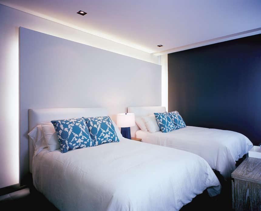 Esta recámara aloja una cama tamaño king, completamente blanca, como el resto del mobiliario del cuarto excepto por toques de azul en los cojines, que resaltan al mismo tiempo que armonizan con el