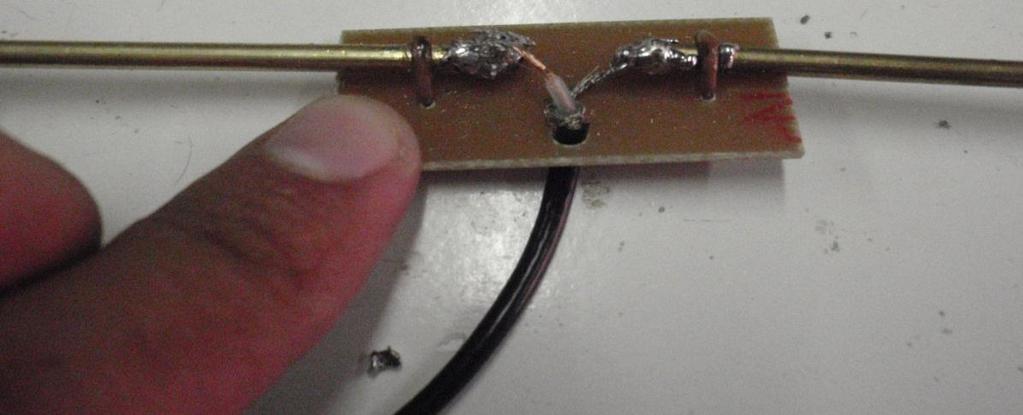 Seguido de esto se debe colocar dos varillas a cada uno de los orificios, seguido de esto pasar el cable coaxial por el cable que tiene en la pista de circuito, soldar el centro del cable a una