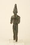 ESTATUILLA MATERIA/SOPORTE MATERIAL: Bronce DIMENSIONES: Altura = 10,30 cm; Anchura = 5 cm DESCRIPCIÓN: Estatuilla del dios Reshef, divinidad guerrera armada de lanza y escudo, que no se han