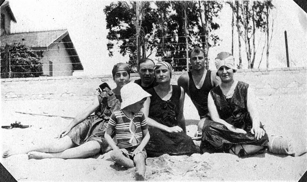 Asseguts a la sorra de la platja, davant del xalet, cap a 1930 Arxiu