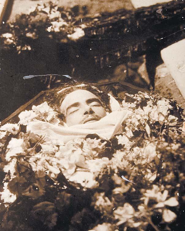 FOTOGRAFÍA DEL POETA MUERTO, de cuerpo presente en el ataúd, abierto para albergar los centenares de rosas y claveles que han depositado sobre su cadáver.