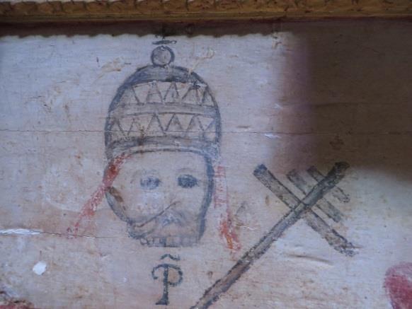 Debajo del altar, se halla pintado sobre fondo blanco, la imagen de un rostro con barba y