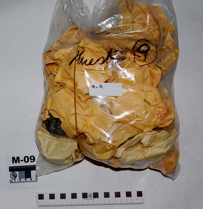 M-9-9 Veinticinco piedras envueltas en sobres de papel, contenidas en una bolsa con la inscripción Muestra 9, situada, junto a las 8 bolsas que contienen las muestras cuya numeración comienza por