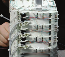 El sistema está basado en 3 componentes principales: el herraje o la zona de la caja destinada a alojar el remanente de tubos de fibras, el módulo para la distribución de fibras y la bandeja de