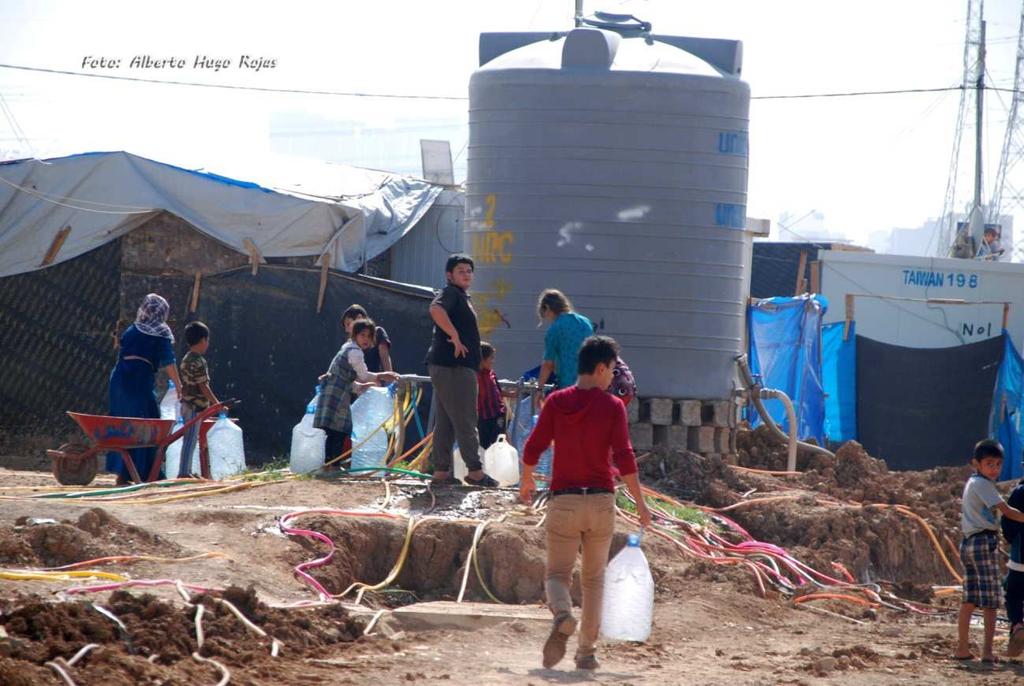 3. Los niños hacen cola para llenar las garrafas de agua y llevarlas en carretilla a sus casas en el campo de refugiados Harsham en Erbil. Kurdistán Iraquí. Iraq 2008.
