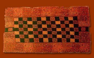 Descripción: Tejido de forma rectangular. De fibras de algodón y lana. Compuesto por un paño central color marrón, dos franjas laterales y 142 flecos cuadrangulares.