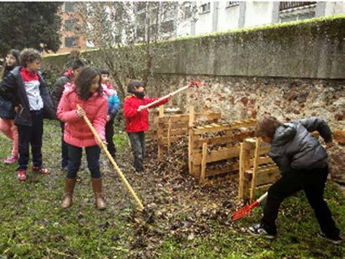 Foto: En esta imagen se observa como los alumnos del Colegio recogen hojas en el patio para elaborar el compost con la ayuda de rastrillos.