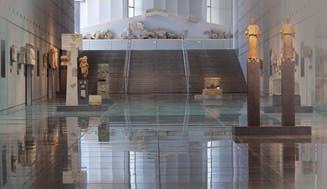 Museo de la Acrópolis LA PLANTA BAJA Antes de pasar por los tornos que dan acceso a la exposición, el museo proyecta un video sobre el mismo en griego e inglés alternativamente, que es interesante.