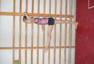 Elevación atrás La gimnasta inicia la evaluación de pie de frente y tomada del espaldar inclinando el torso al frente hasta la horizontal.