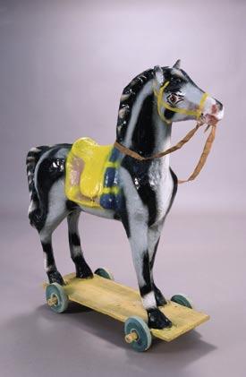 13. Caballo. Figura de caballo realizada en cartón piedra pintada de negro y blanco, Tanto la silla como el cabezal están pintados de amarillo y azul.