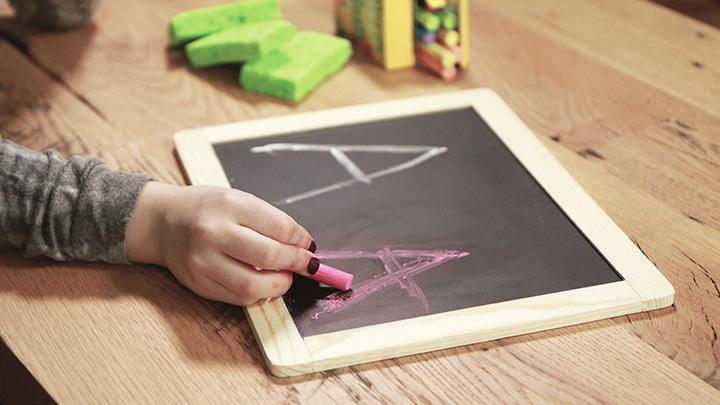 Usted también puede trazar las líneas de arriba y abajo con pegamento. Cuando seque, el lápiz de su hija tropezará con esas líneas al escribir.