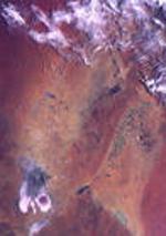 Foto de la Tierra donde principalmente se muestra terreno, acompañado de una pequeña sección de nubes.