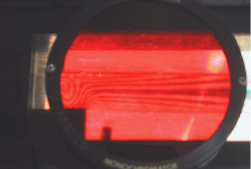 3 2017) Aplique carga con el (los) tornillo(s) hasta generar un patrón de líneas isocromáticas y luego coloque el filtro rojo sobre el polariscopio (para un correcto conteo de las