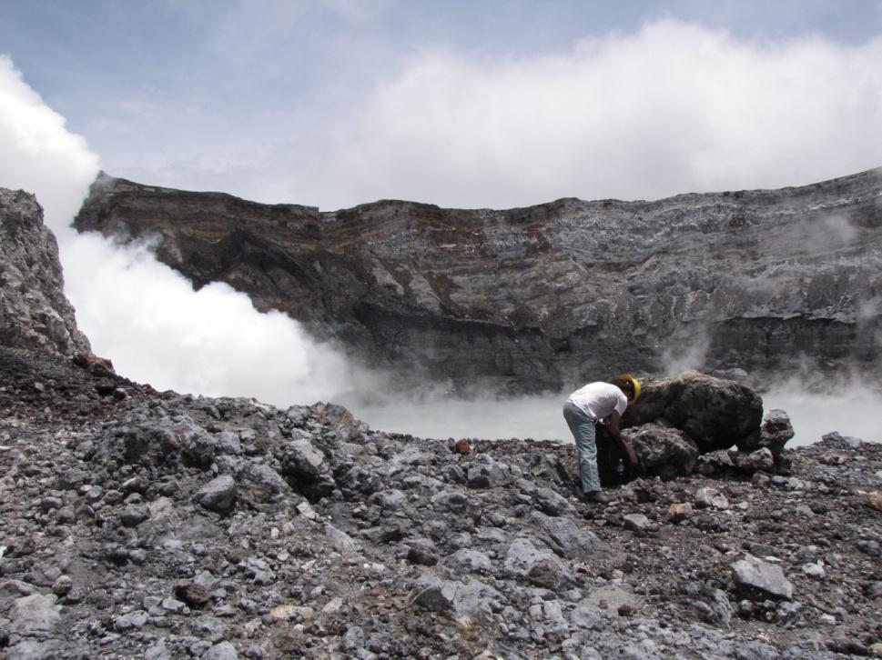 Foto 3: Toma muestras de azufre y líticos hidrotermalizados que el lago del Poás lanza con sus erupciones freáticas. Al fondo, al lado izquierdo, el domo emanando gases a alta temperatura (R. Mora).
