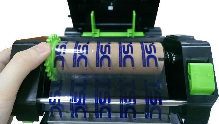 7. Tire del inicio de la cinta a través del cabezal de impresión y pegue dicho inicio en el núcleo de papel de rebobinado de la cinta. 8.