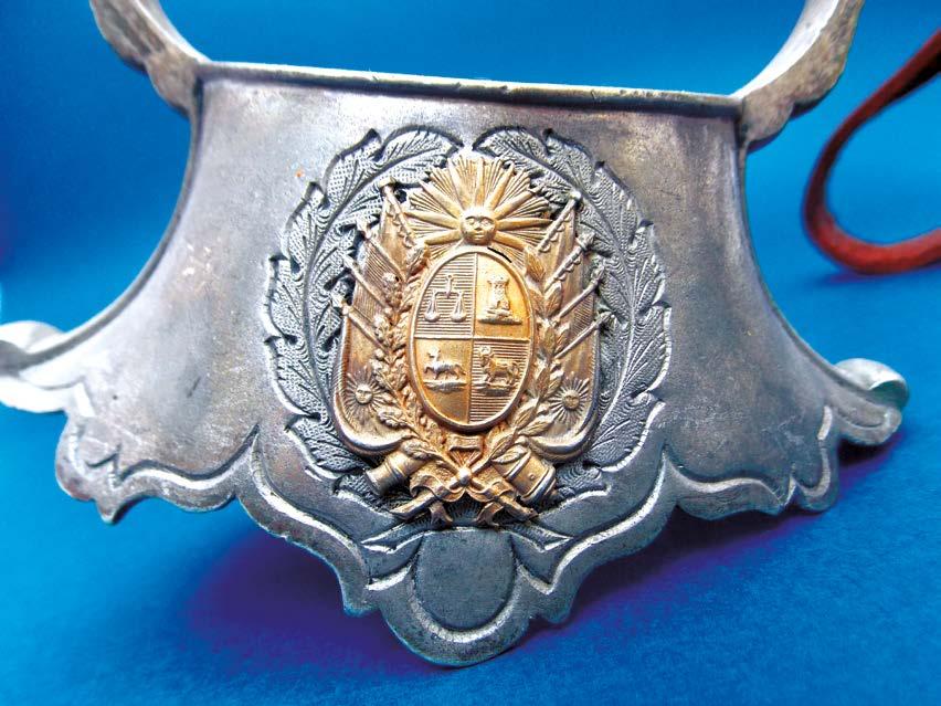 2 - Par de estriberas con pasadores y estribos en metal blanco, decorados Escudo Nacional antiguo en bronce. 3 - Carona en cuero repujado con aplicaciones de yaguareté.