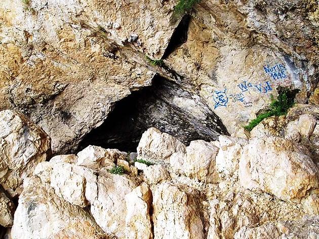El gran abrigo de la pared Sur del Montgó, que es visible desde todo el valle, constituye la entrada de la cueva. El amplio abrigo está plagado de bloques de piedra desprendidos desde el techo.